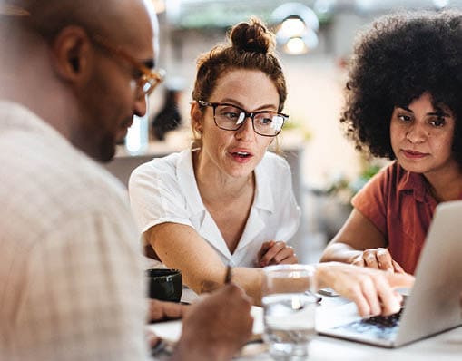 Business women having a work lunch in a caf , exchanging ideas and discussing their projects with a client. Young business team using a laptop as they sit around a coffee table.