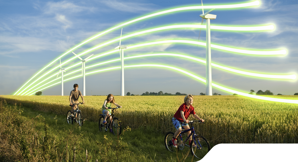 3 children on bicycles in front of wind turbines in a wheat field.