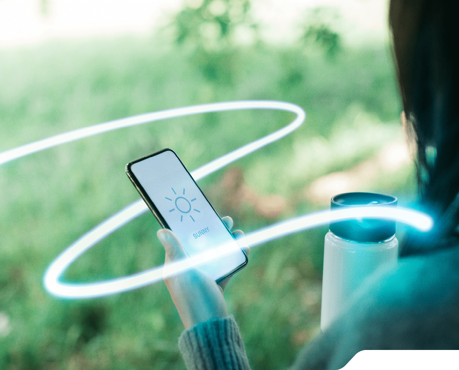 Over the shoulder view of a woman looking at weather forecast using mobile app on smartphone and holding a travel mug 