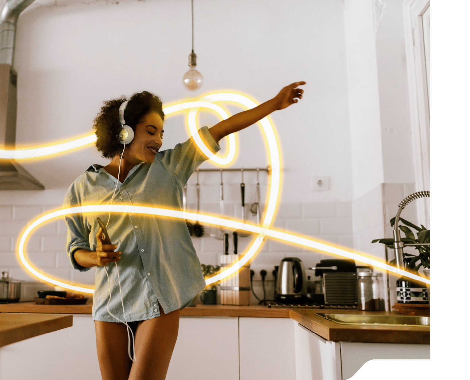 Woman dancing and listening music in the morning in her kitchen