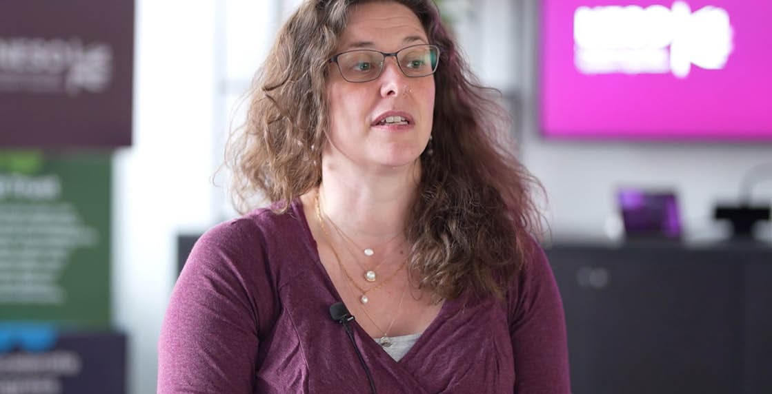 A woman wearing a purple shirt and glasses. Description generated by AI