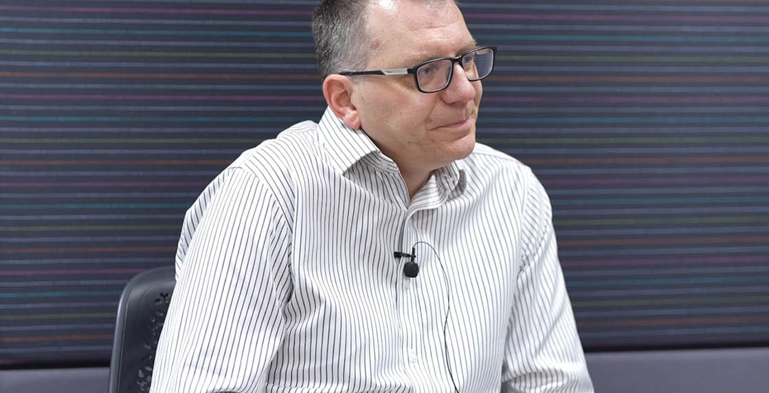 A man wearing glasses and a white shirt. Description generated by AI
