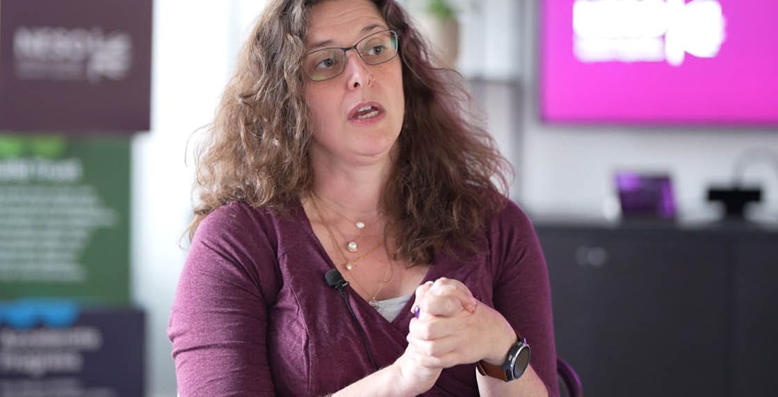 A woman wearing a purple shirt and glasses. Description generated by AI