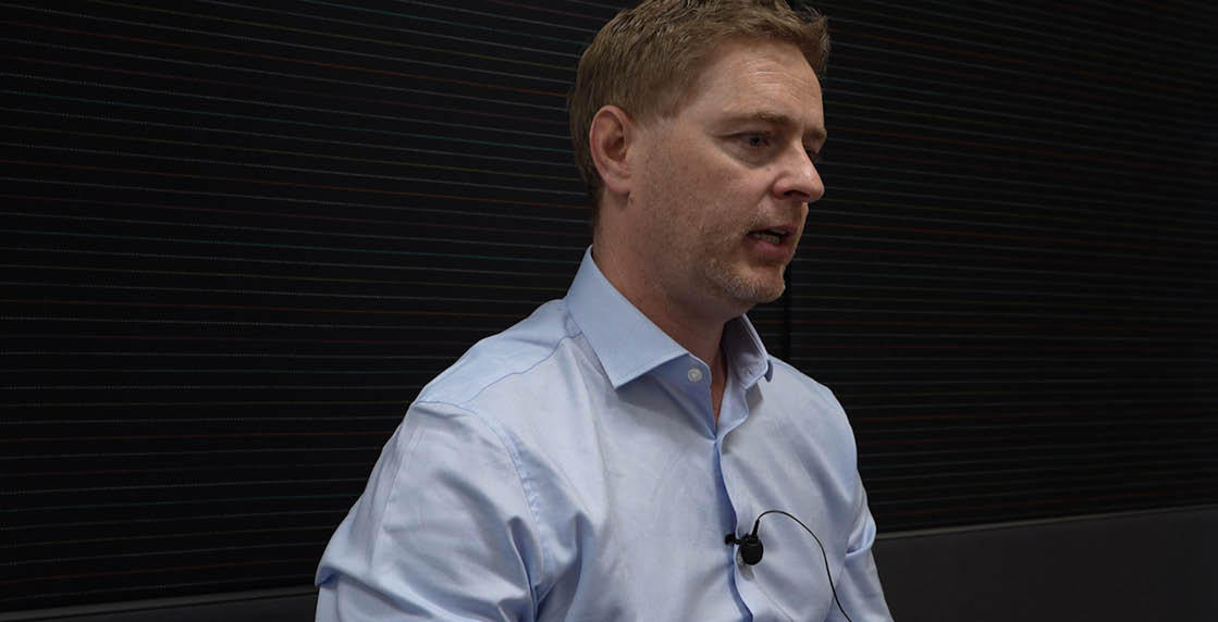 A man wearing a blue shirt and a microphone. Description generated by AI